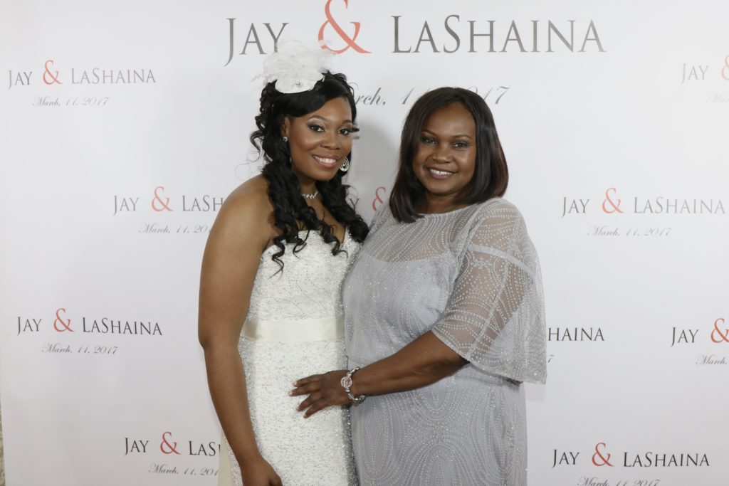 bride and guest in front of custom step and repeat