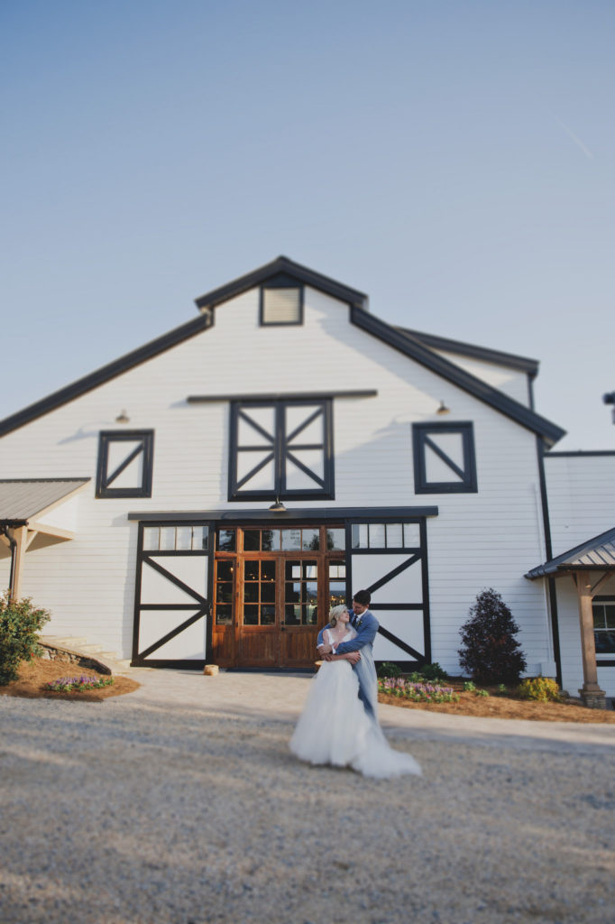 modern & romantic bride in groom in front of barn wedding venue