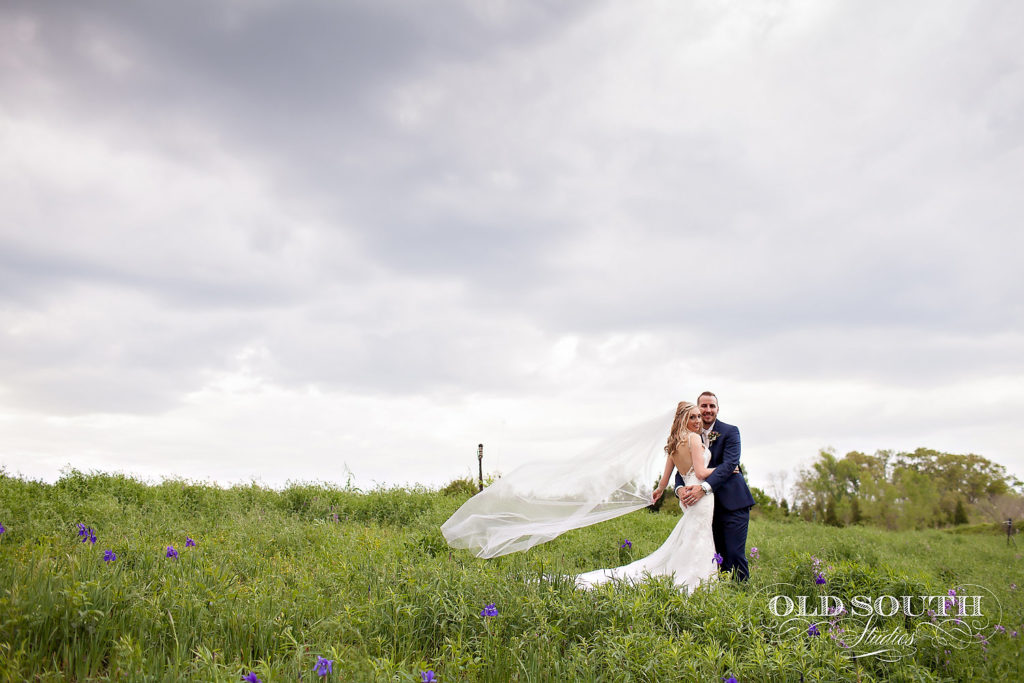 Bride and groom posing in a field for wedding video and photo