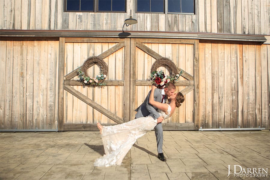 The bride and groom kissing in front of a barn. 