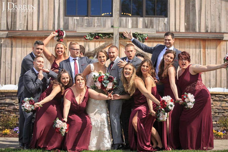 The bride and groom and their friends and family in front of a barn. 