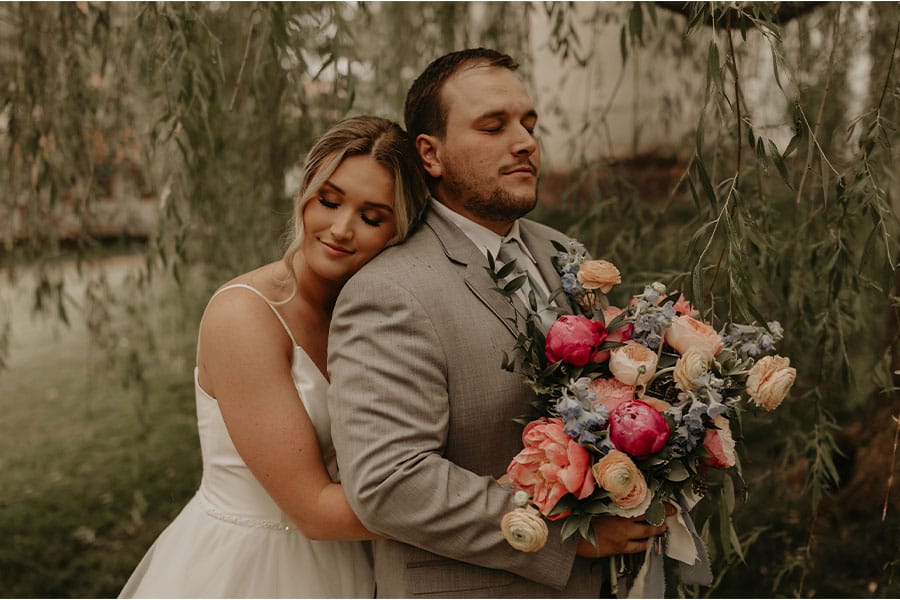 The bride and groom holding each other with flowers. 