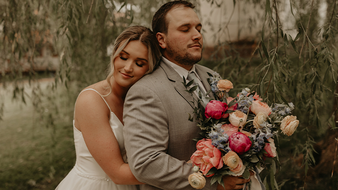 The bride and groom holding each other with flowers.