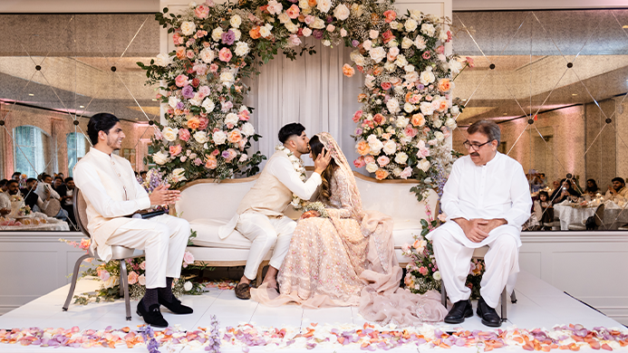 The bride and groom kissing with floral structure in the background.