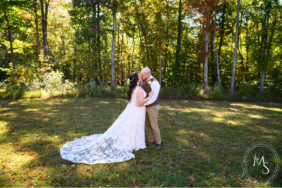 The bride and groom kissing in front of woods.