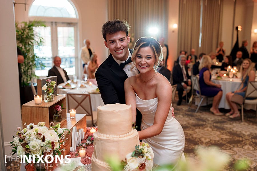 The bride and groom cutting their wedding cake. 