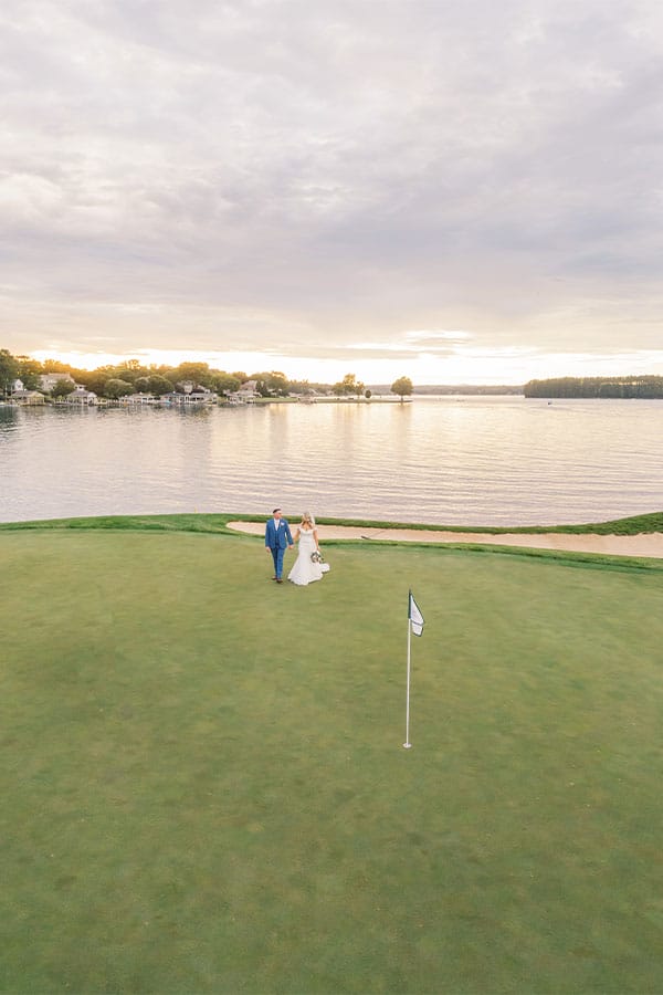 The bride and groom walking by the lake. 