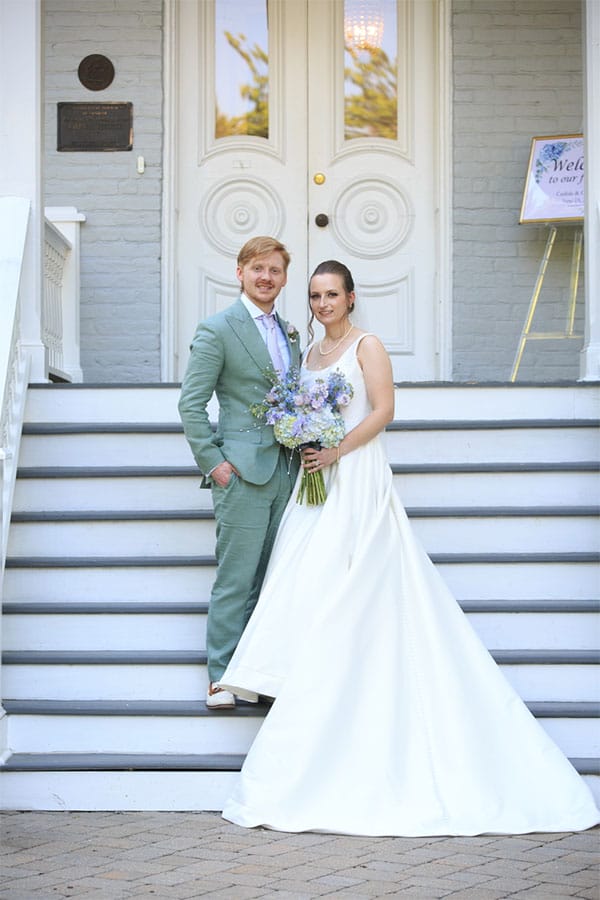 The bride and groom standing on a stair case together.