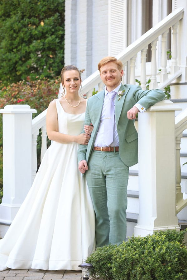The bride and groom standing on a stair case together.
