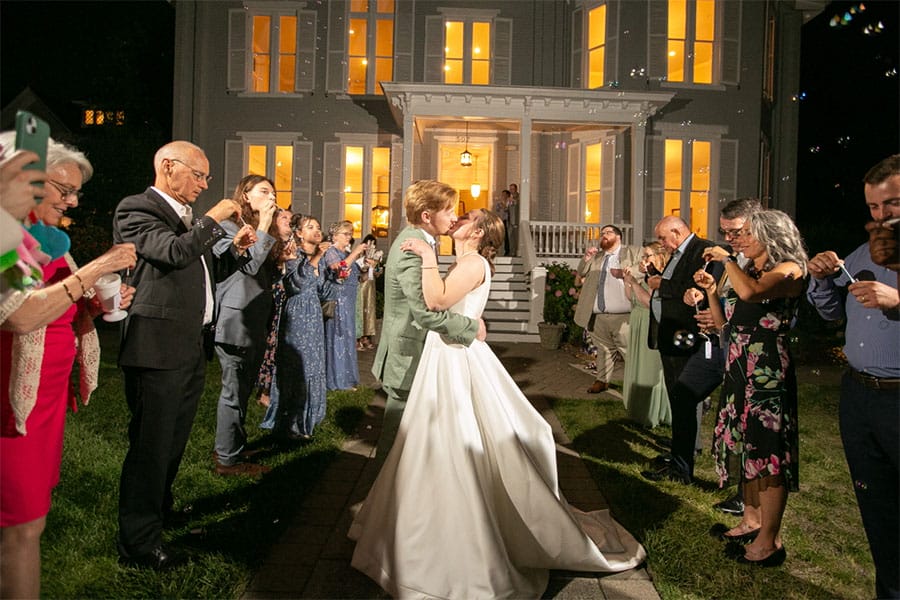 The bride and groom kissing in front of the wedding venue.