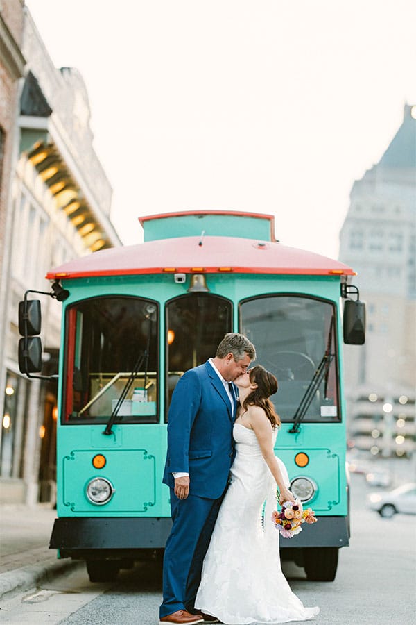 The bride and groom in front of a bus.