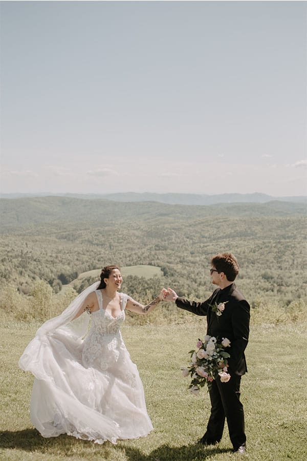 The bride and groom in front of a field holding hands. 