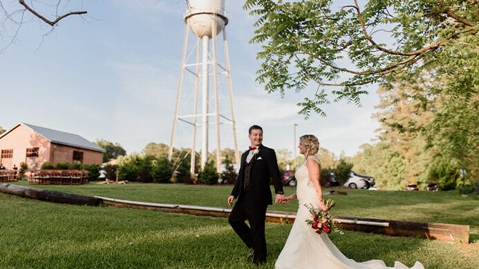 bride and groom walking by water tower