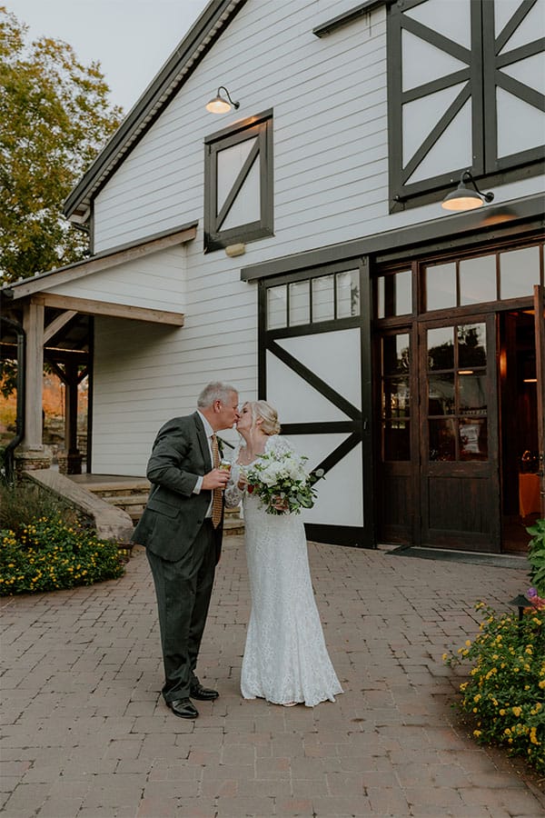 The bride and groom kissing in front of a beautiful barn. 