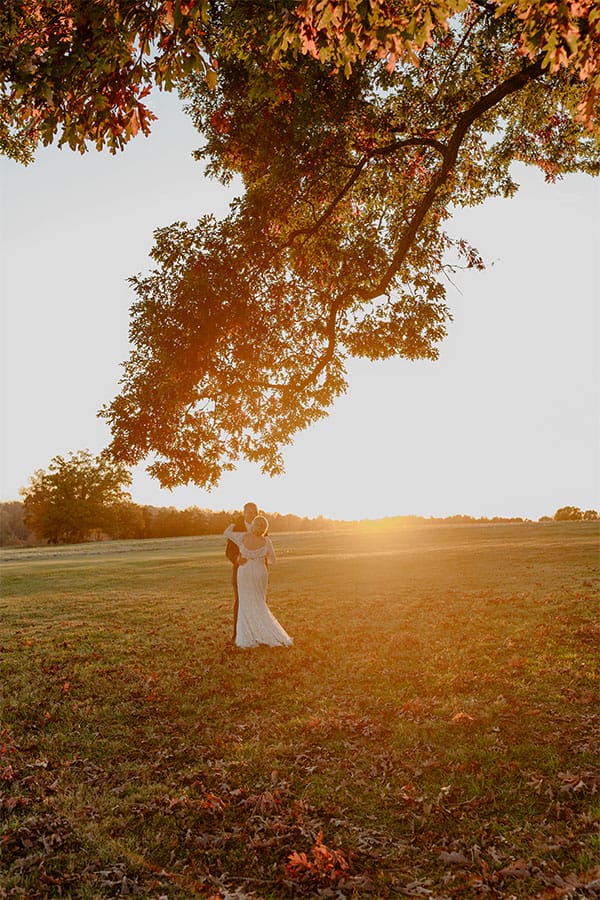 The bride and groom kissing in a field. 