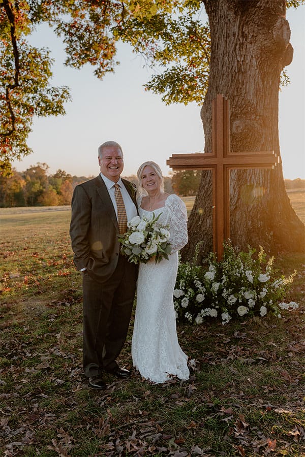 The bride and groom standing in front of a beautiful cross. 