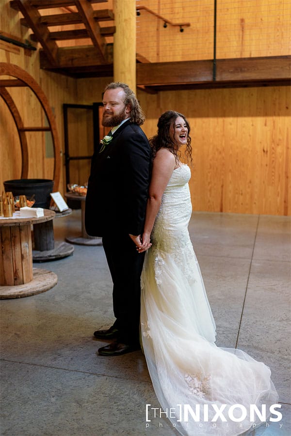 The bride and groom standing back to back. 