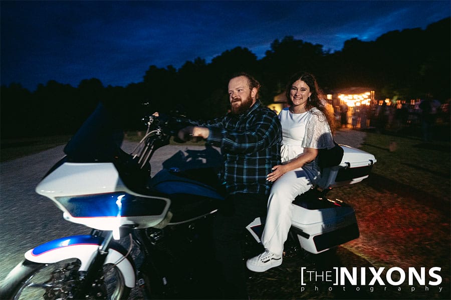 The bride and groom leaving the wedding venue on a motorcycle. 