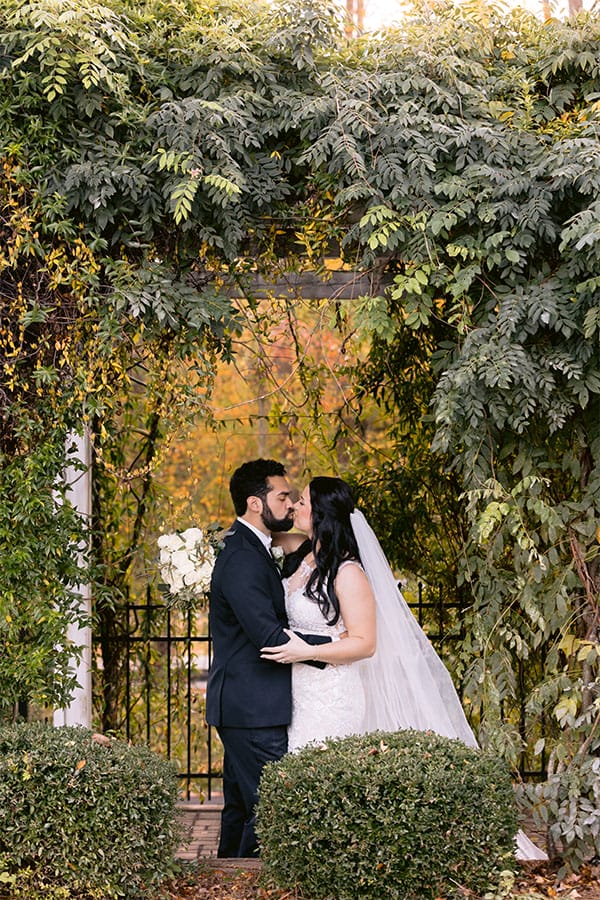 The bride and groom kissing with beautiful greenery.