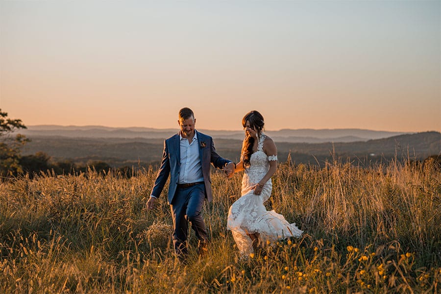 The bride and groom walking in a field together. 