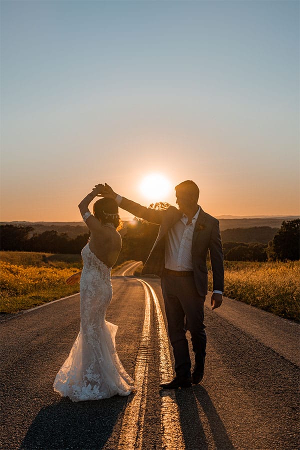 The bride and groom standing together iin the road.