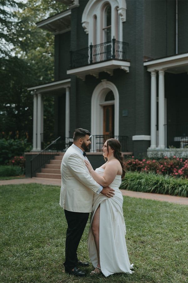 The bride and groom in front of a beautiful house.