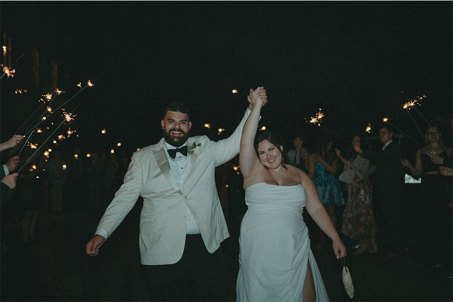 The bride and groom holding hands with lights in the background. 