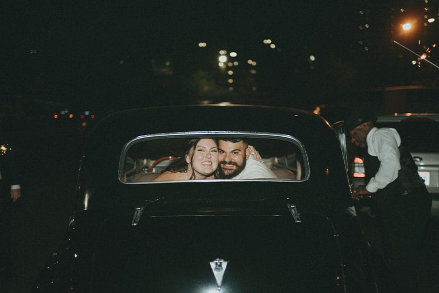 The bride and groom in the back of a car. 