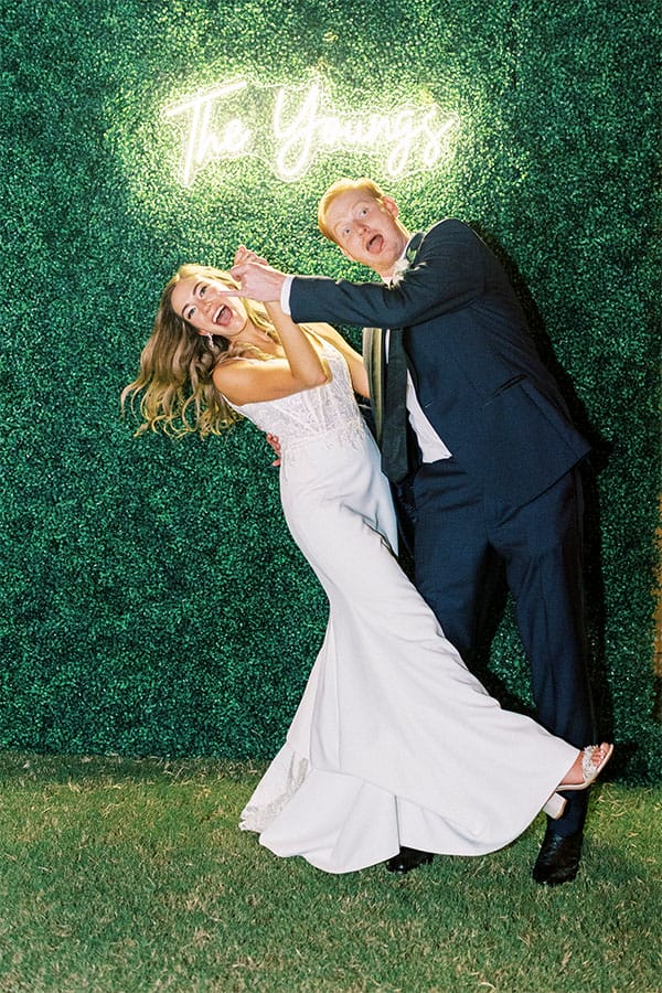 The bride and groom in front of a sign. 