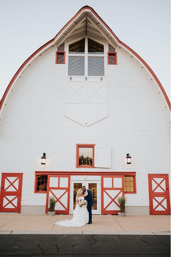 The bride and groom in front as beautiful barn.